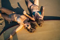 两名女子在越南阳光明媚的海滩上放松身心，旁边是桨板，享受夏日的氛围