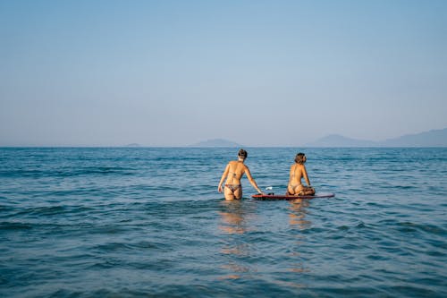 Woman in Bikini Sitting on Paddle Board in the Ocean
