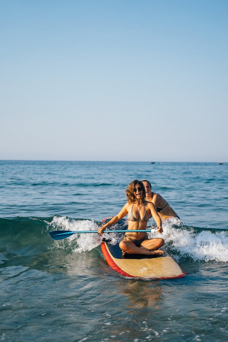 Woman Sitting On Paddle Board Paddling