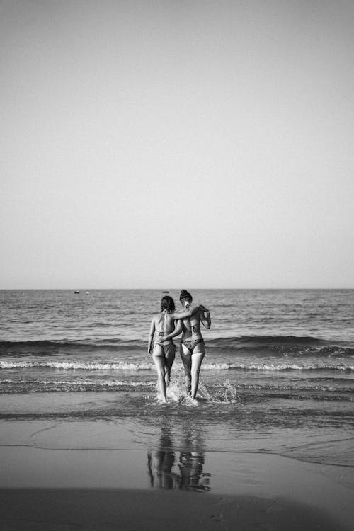 Grayscale Photo of Women Walking Towards the Sea