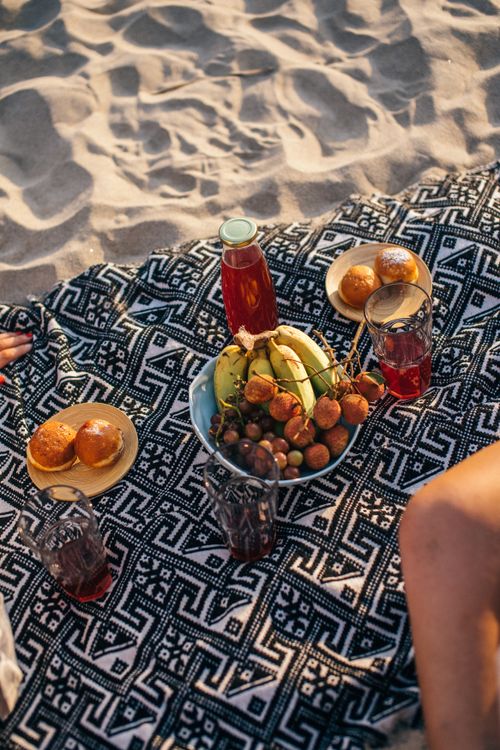 Free Enjoy a relaxing beach picnic in Vietnam with fresh fruits and bread on a patterned blanket. Stock Photo