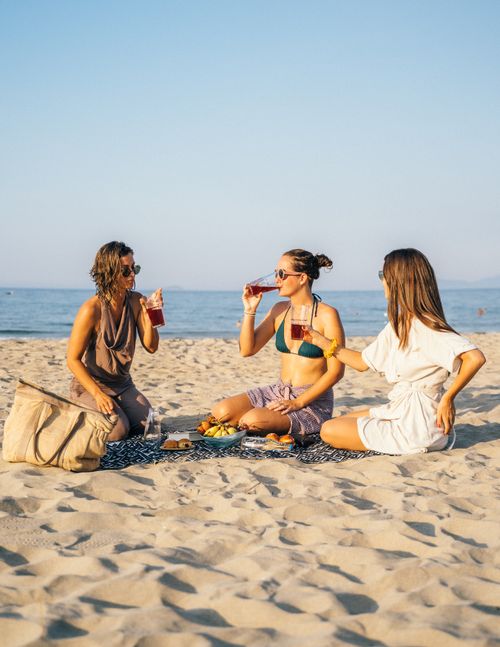 Free Three women relaxing and enjoying a picnic on a sunny beach in Vietnam. Stock Photo