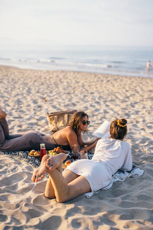 Free Women Lying on the Beach while Having Conversation Stock Photo