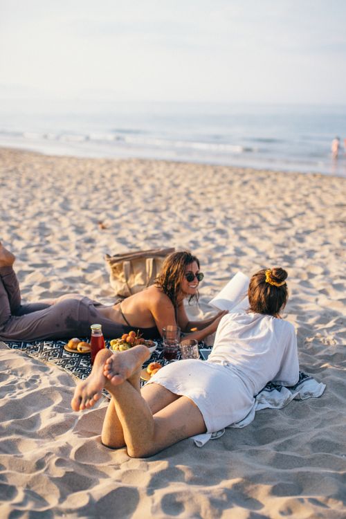 Free Two women enjoy a relaxing beach picnic with snacks and conversation in Vietnam. Stock Photo