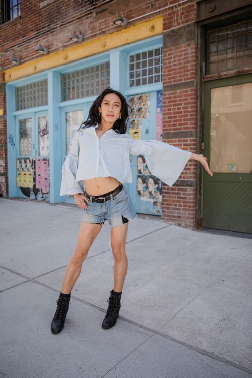 Free Stylish model poses confidently in an urban setting wearing denim shorts and a crop top. Stock Photo