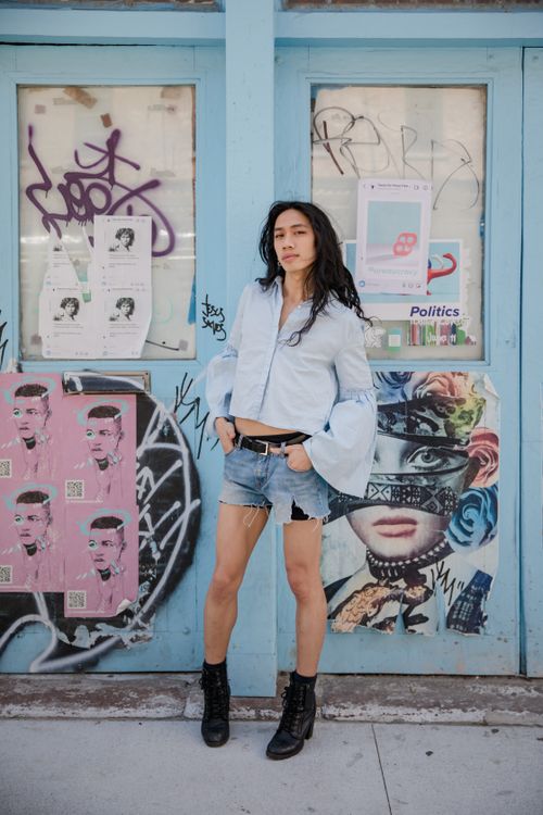 Free Stylish young woman standing against a graffiti wall in urban setting. Stock Photo