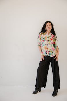 Studio portrait of stylish woman wearing floral shirt and black pants.