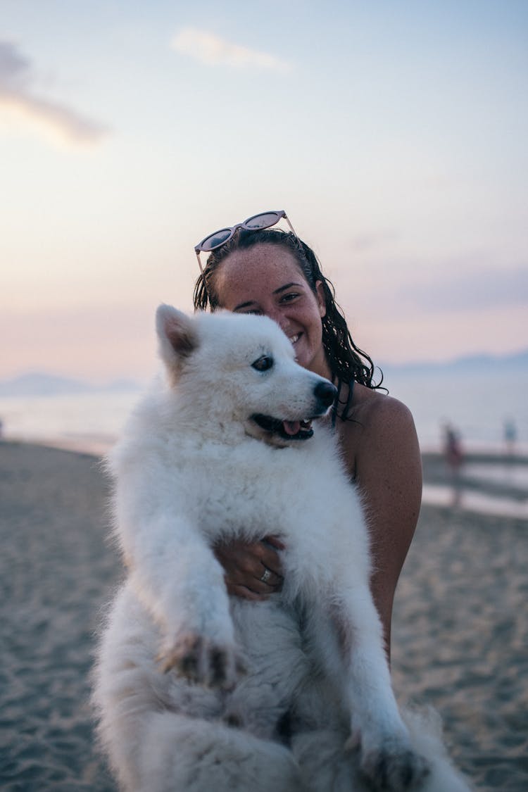 A Woman Carrying Her Dog On The Beach