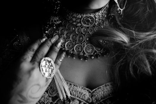 Black and white close-up of intricate jewelry with manicured hand and elaborate designs.