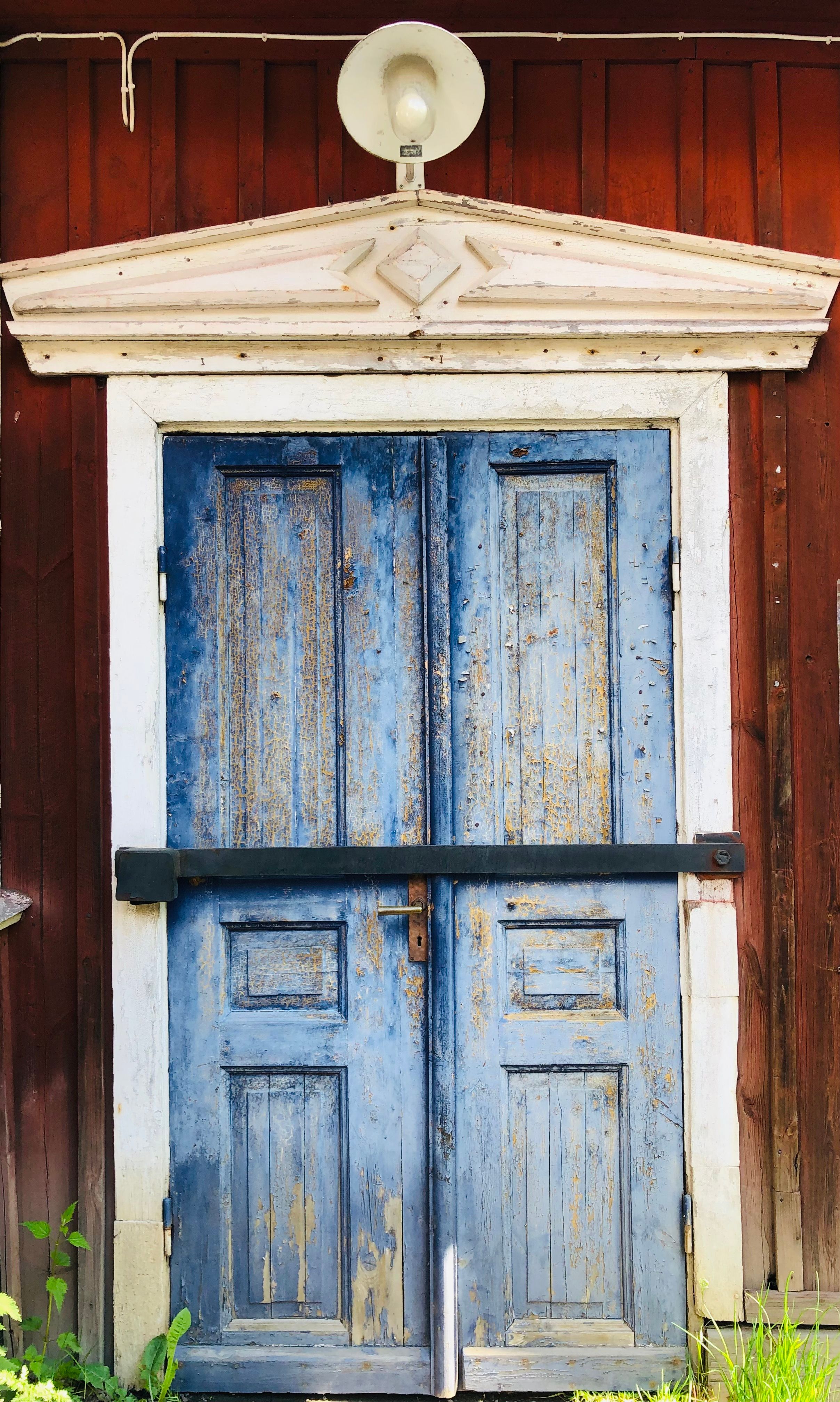 Close-up of aged blue wooden doors on a rustic barn, showcasing weathered texture and rural charm.