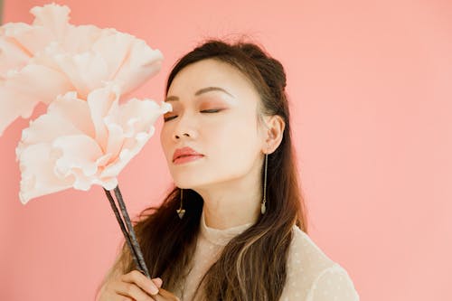 A Woman Holding a Flower While Eyes Closed 