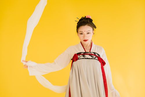 Free Portrait of an Asian woman in traditional Hanfu against a yellow background. Stock Photo