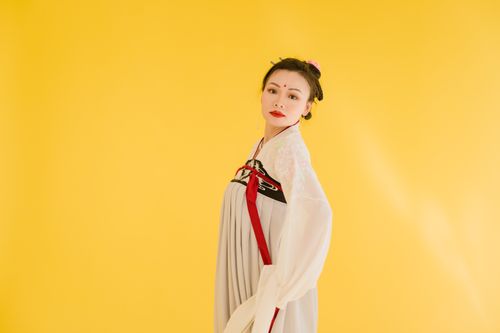 Free Elegant portrait of a woman in traditional Hanfu dress set against a vivid yellow backdrop. Stock Photo