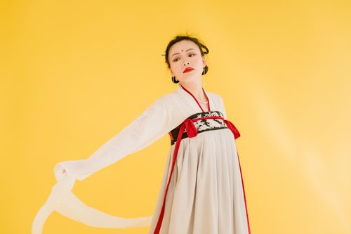Free Portrait of a woman in traditional hanfu attire against a vibrant yellow backdrop. Stock Photo