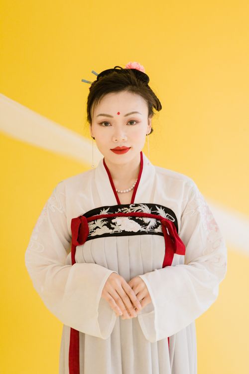 Free Elegant woman in traditional hanfu attire against a bright yellow backdrop. Stock Photo