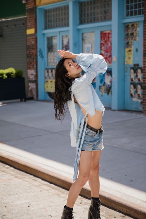 Free Trendy woman in denim shorts posing confidently on a sunny city street. Stock Photo