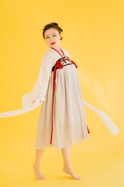 Free Portrait of a woman in traditional Hanfu fashion posing gracefully against a yellow backdrop. Stock Photo