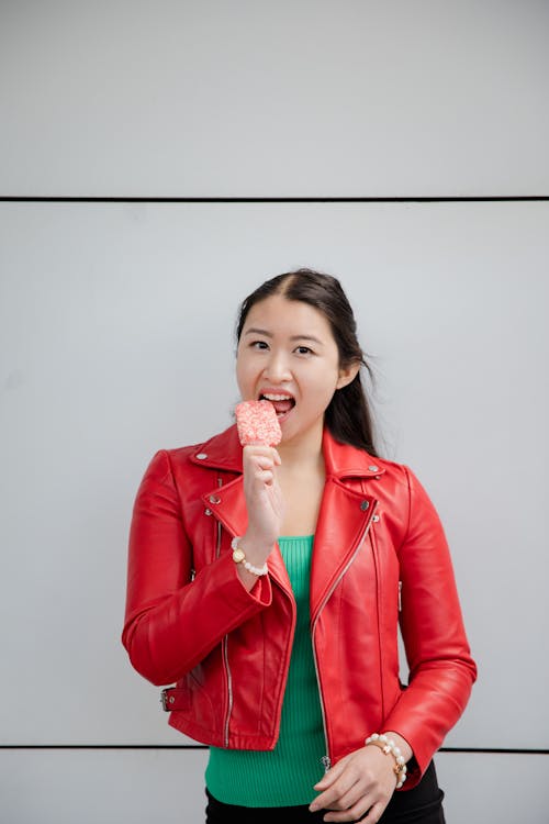 A Woman Wearing Red Leather Jacket while Eating Ice Cream