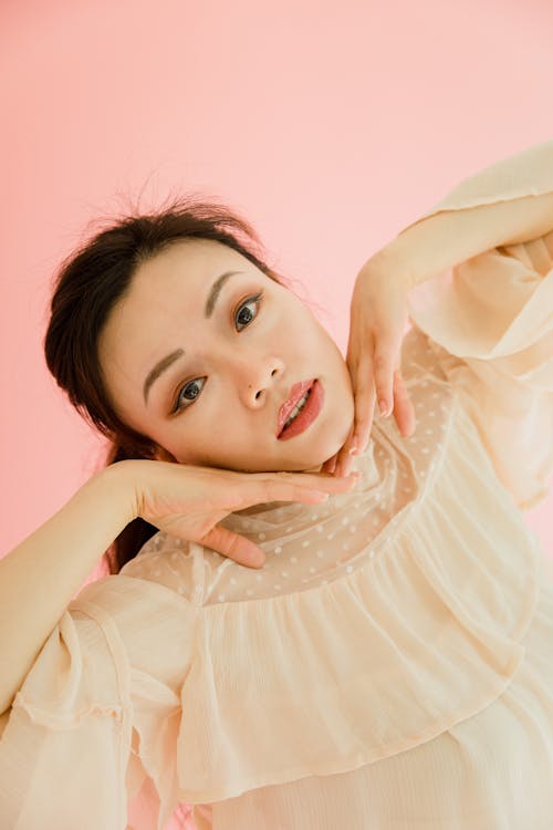 A Woman in Peach Dress Touching Her Face