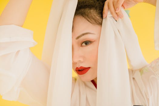 Striking portrait of a woman in white fabric against a yellow background, emphasizing elegance and beauty.