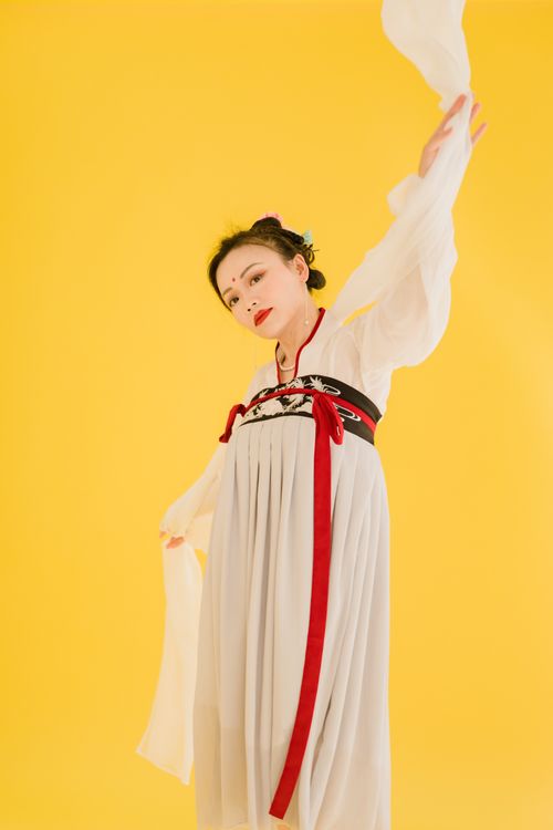 Free Artistic portrait of an Asian woman posing elegantly in a traditional dress against a vibrant yellow background. Stock Photo