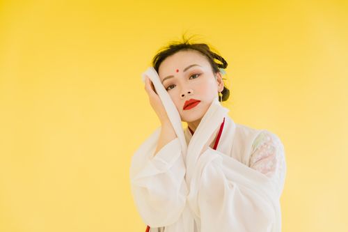 Free A striking portrait of a woman in traditional wear set against a vibrant yellow backdrop. Stock Photo