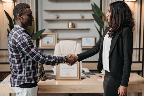 Free Two professionals shaking hands in an office, symbolizing a successful business agreement. Stock Photo