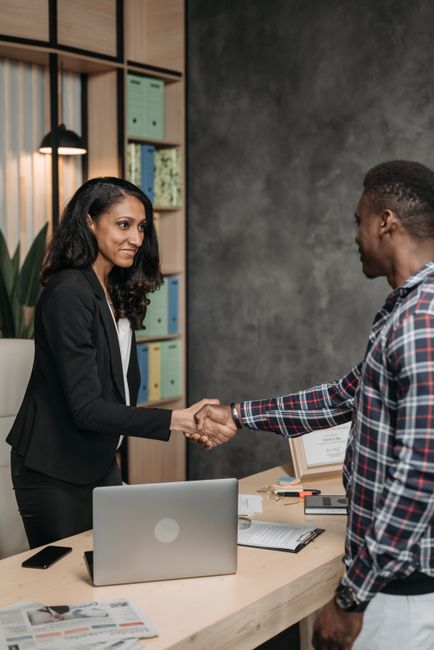 Two professionals shaking hands in an office setting, symbolizing a successful business partnership