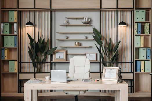 Luxurious office setup with a desk, laptop, plants, and decor in a stylish interior.