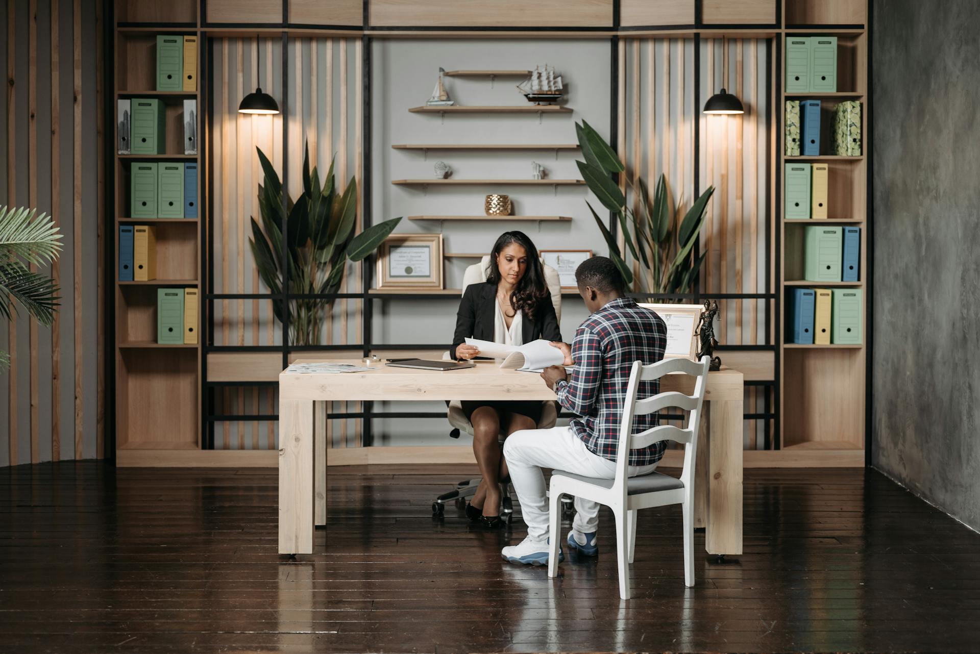 A lawyer consulting a client in a modern office with organized paperwork and decor.