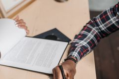 Hands of a person signing official documents on a desk in an office setting.