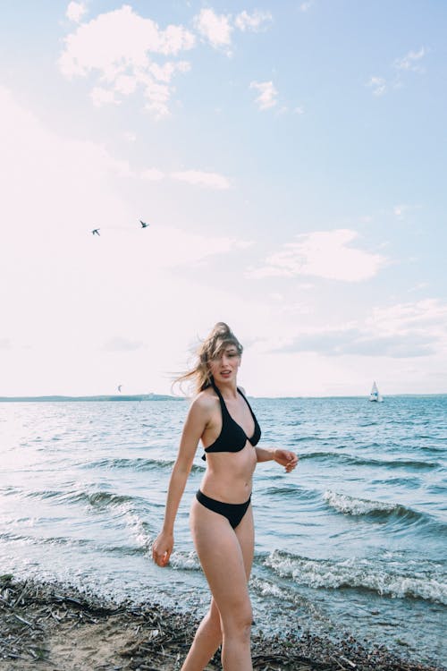 Free Woman in Black Bikini Standing on Sea Shore Stock Photo