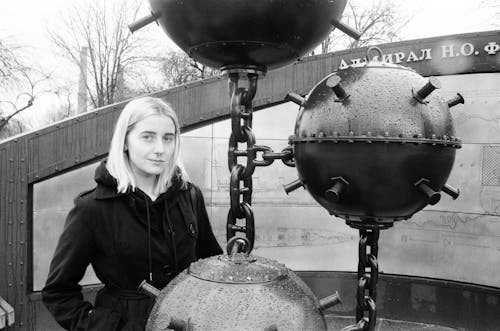 Monochrome Photo of Woman standing beside Metal Buoys