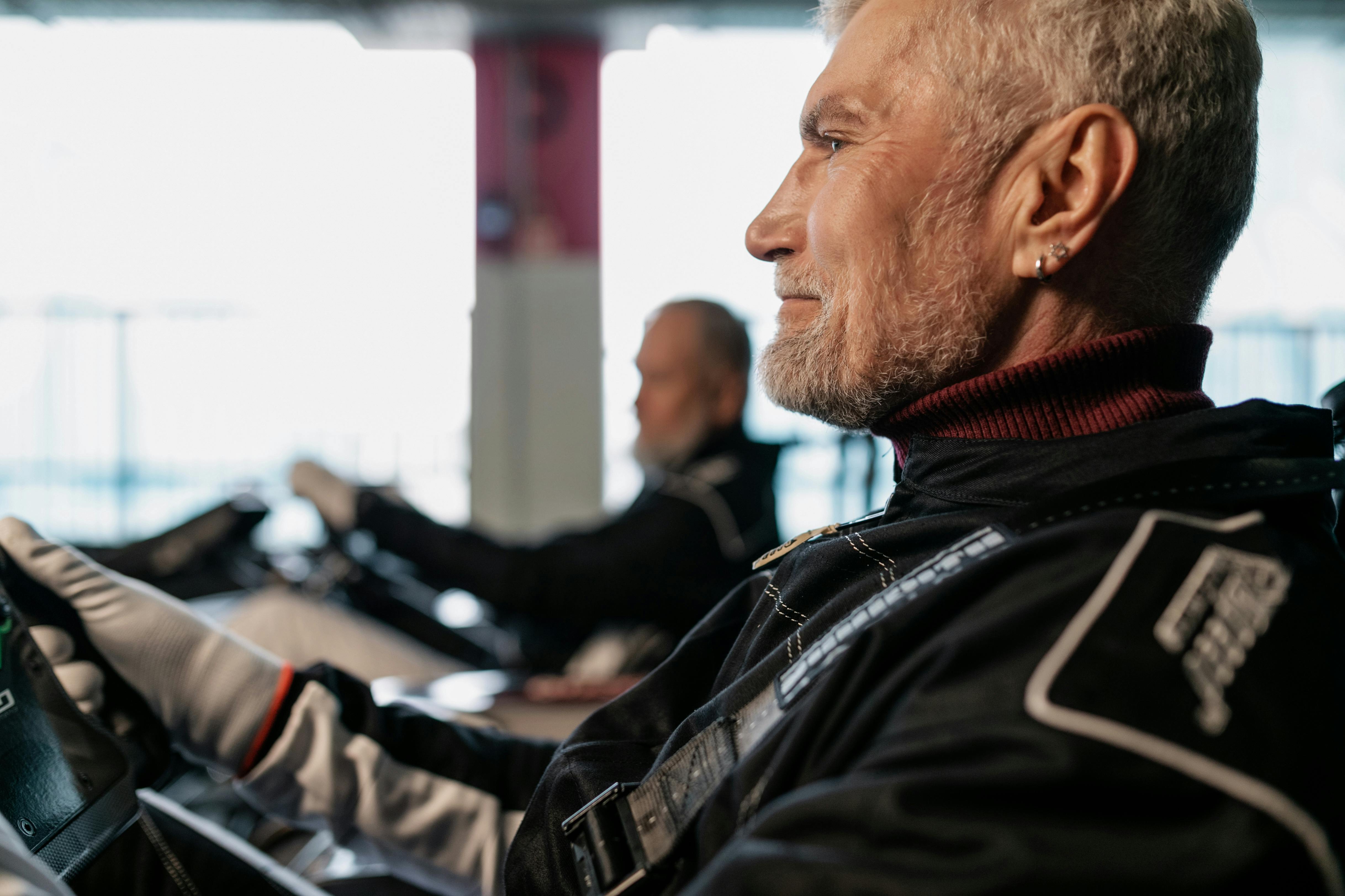 Side view of a senior man in racing gear, participating in indoor kart racing.