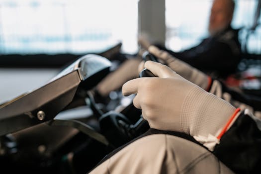 A focused shot of a racer's gloved hands gripping the wheel of a go-kart, showcasing racing gear and motion.