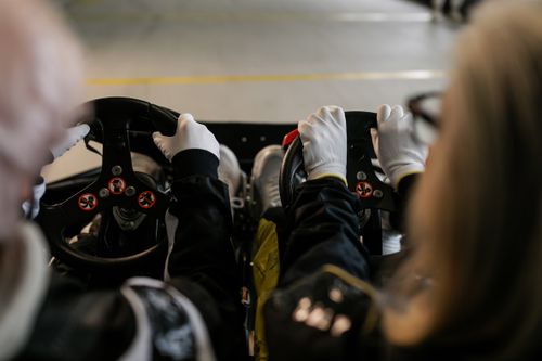Free Close-up view of go-kart racers driving with gloves gripping steering wheels indoors. Stock Photo