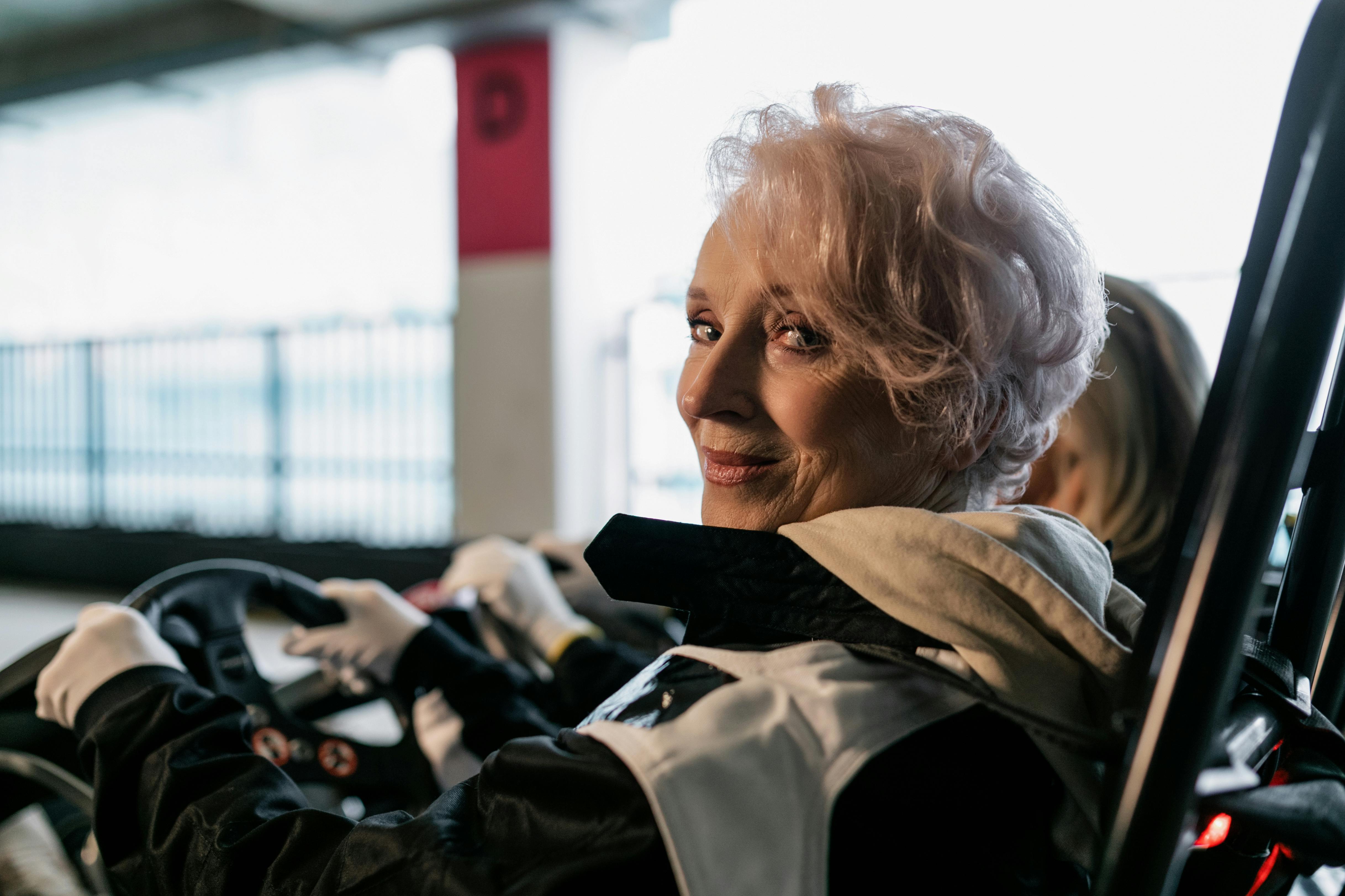 A cheerful senior woman enjoying indoor go-kart racing, highlighting active living.