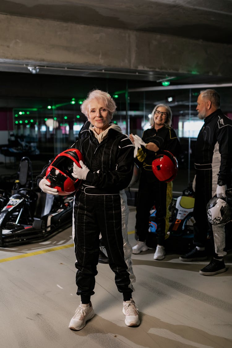 Elderly Woman Wearing Racing Suit Holding Red Helmet 