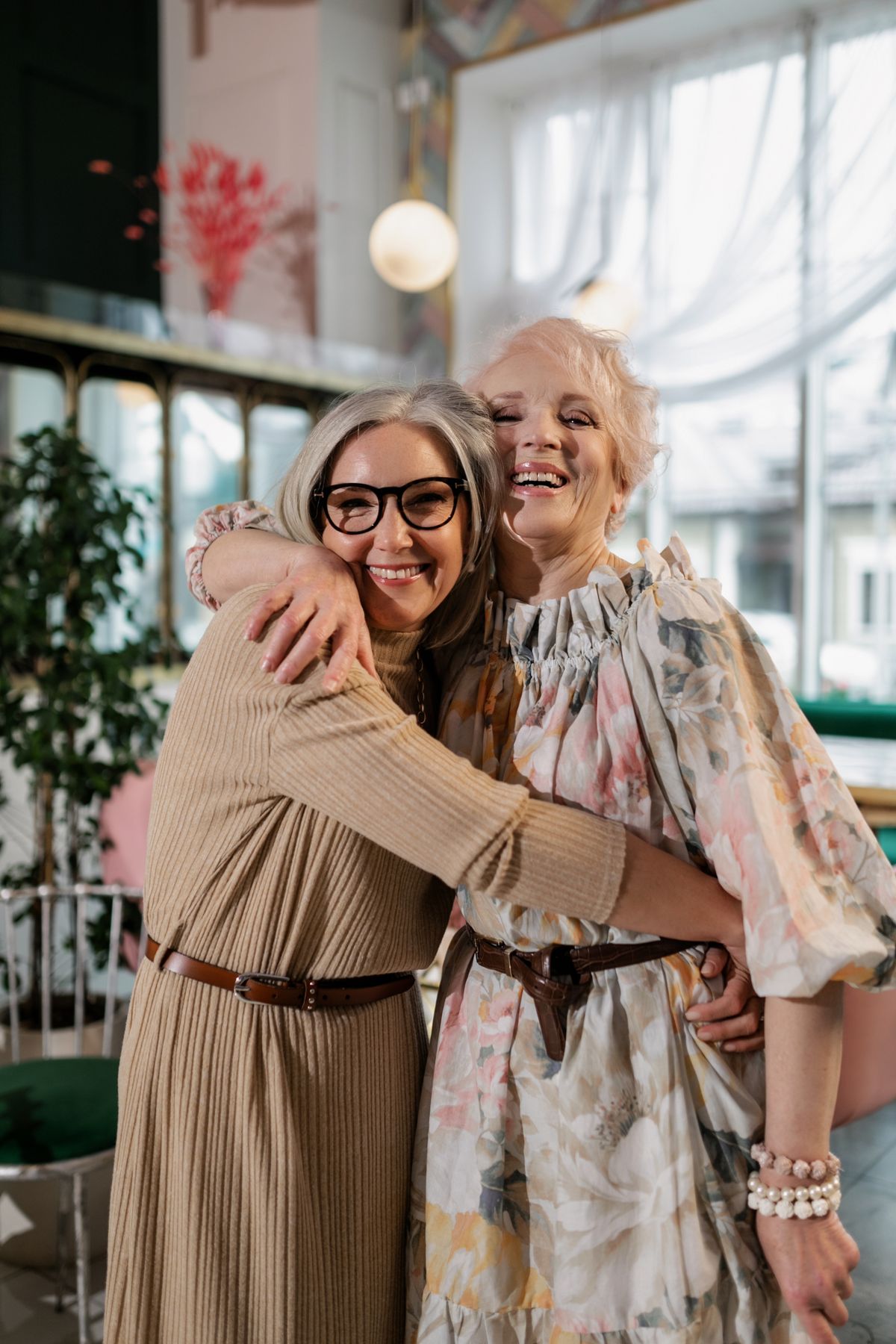 Two older friends sharing a warm embrace indoors