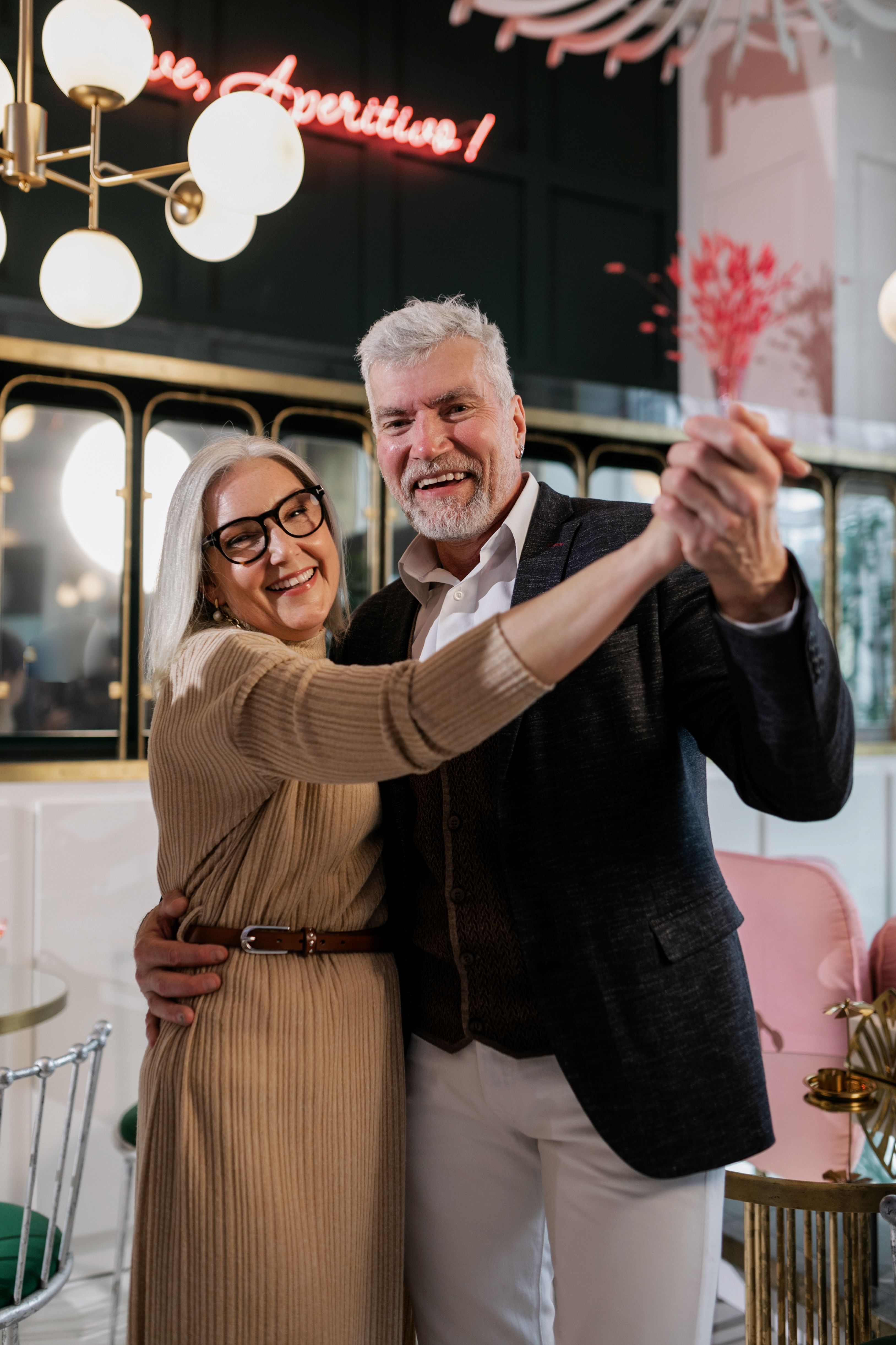 Happy senior couple dancing together in an elegant indoor setting, showcasing love and joy.