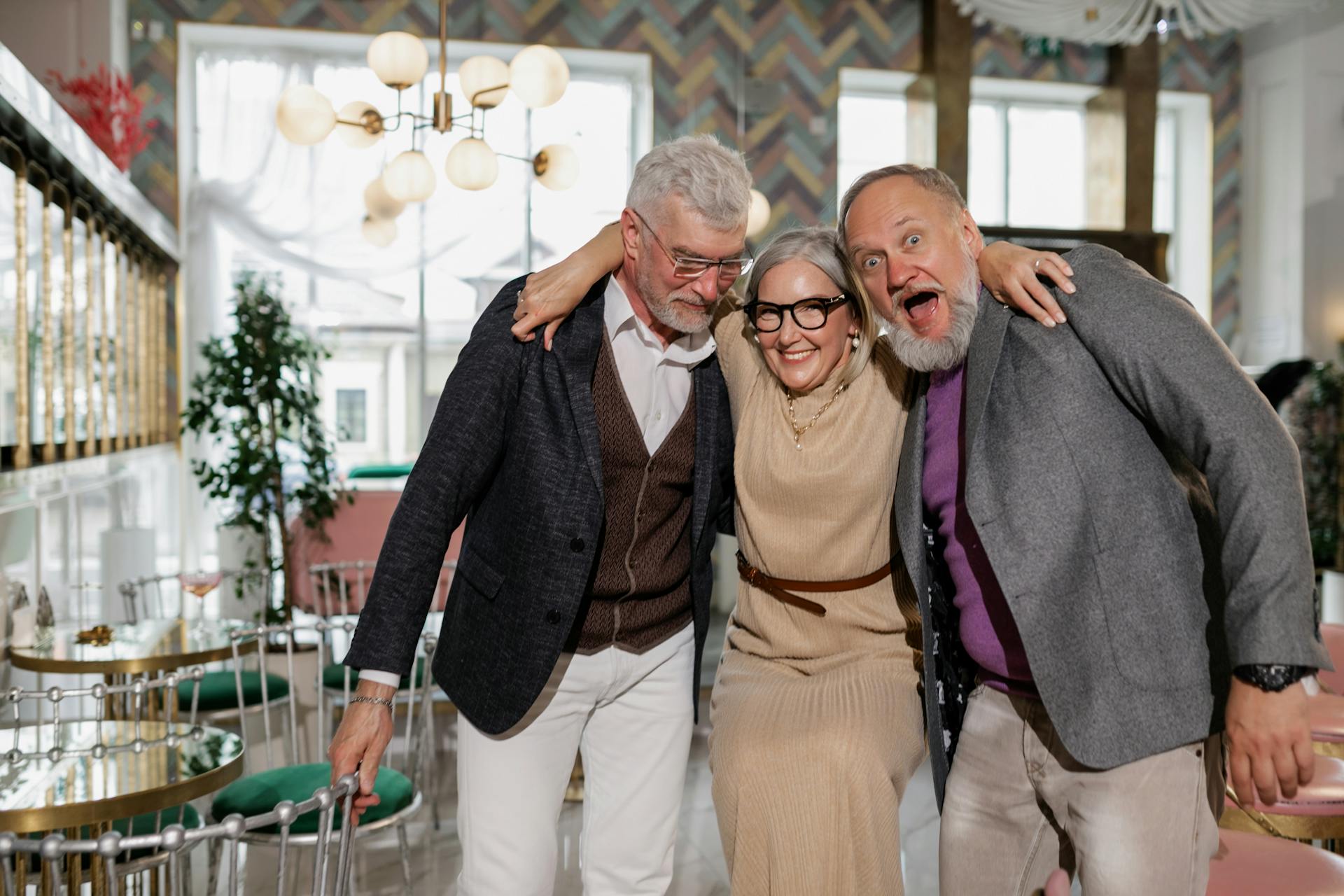 Elderly friends laughing and hugging at a lively indoor café setting, showcasing friendship.