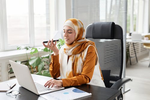 Woman in Front of a Laptop Talking on the Phone