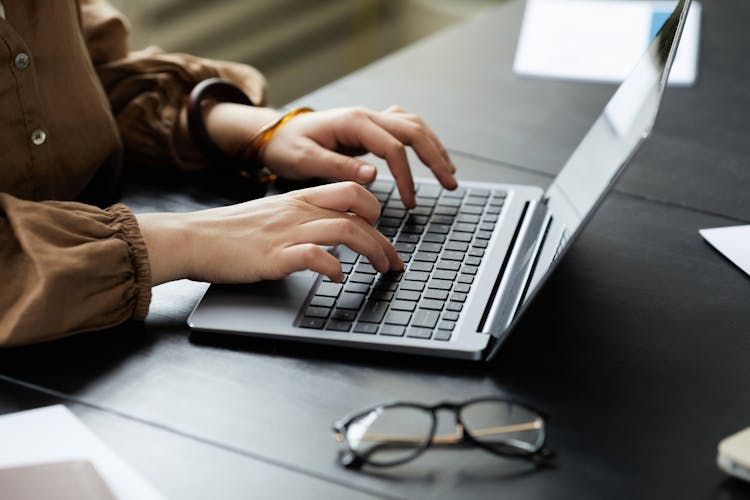 A Person Typing On A Laptop 