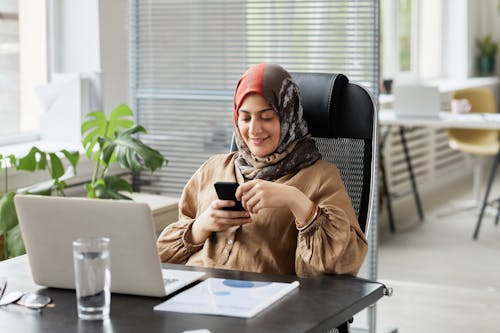 Woman in Brown Long Sleeve Shirt Using Smartphone