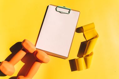 Dumbbells and a clipboard on yellow, photo by Alesia Kozik on Pexels