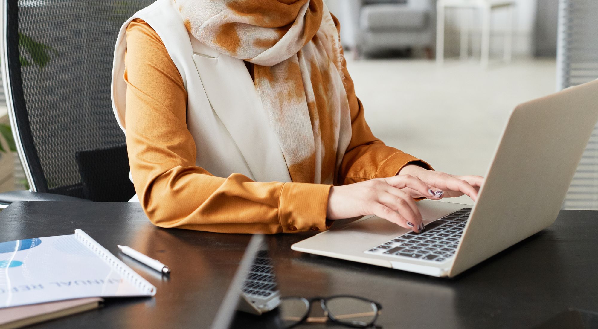 A marketer working on a laptop in a bright office