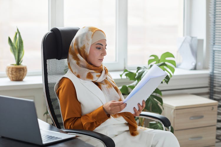 Woman Sitting On Black Office Chair Reading A Paperwork