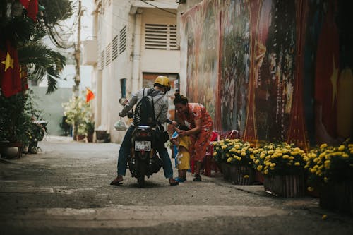 A Person Riding the Motorcycle Beside a Woman and a Child