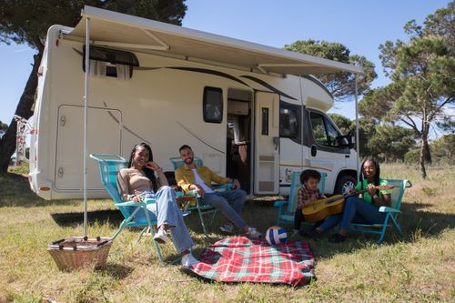 Free Smiling family enjoying a camping trip in Portugal with their campervan, relaxing with leisure activities. Stock Photo