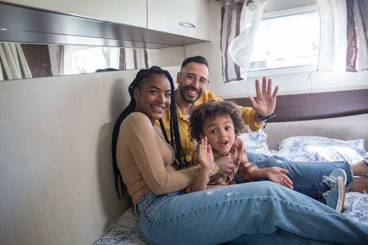 Photo Of A Happy Family Sitting On Bed Inside A Camper Van